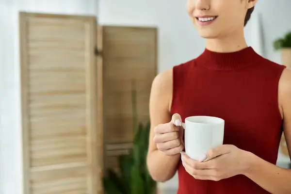 A young woman in a red tank top enjoys her morning tea at home, radiating a calm and peaceful routine. — Stock Photo