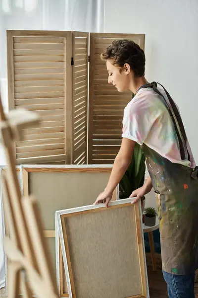 Una joven vestida con un atuendo casual se prepara para crear una hermosa pintura en su acogedor espacio hogareño. - foto de stock