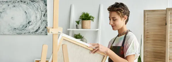 Una joven con maquillaje natural se dedica a la pintura, inmersa en su proceso creativo en casa. - foto de stock