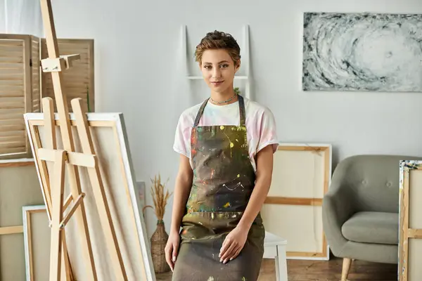 En un acogedor estudio en casa, una joven con maquillaje natural pinta apasionadamente una nueva obra de arte. - foto de stock