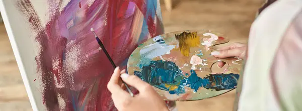 A young woman enjoys expressing her creativity by painting at home, working intently on her artwork. — Stock Photo
