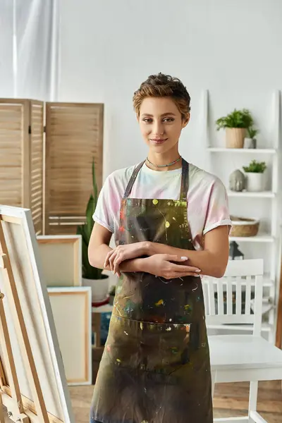 Una joven de pelo corto disfruta pintando en su alegre estudio, expresando su espíritu artístico. - foto de stock