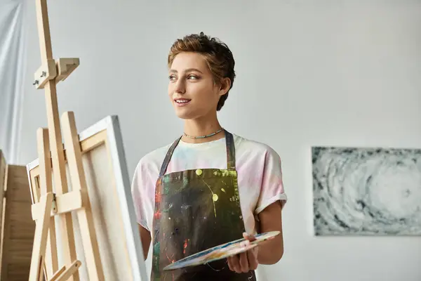 This young woman enjoys painting in her cozy home, showcasing her passion for art with a smile. — Stock Photo