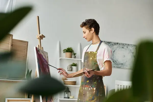 Em um ambiente acolhedor em casa, uma jovem mulher explora apaixonadamente sua criatividade enquanto pinta uma obra de arte vibrante. — Fotografia de Stock