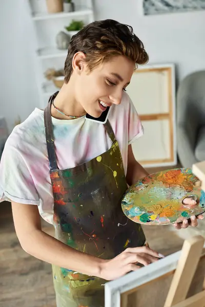 A young woman with natural makeup and vibrant short hair expresses her creativity while painting at home. — Stock Photo