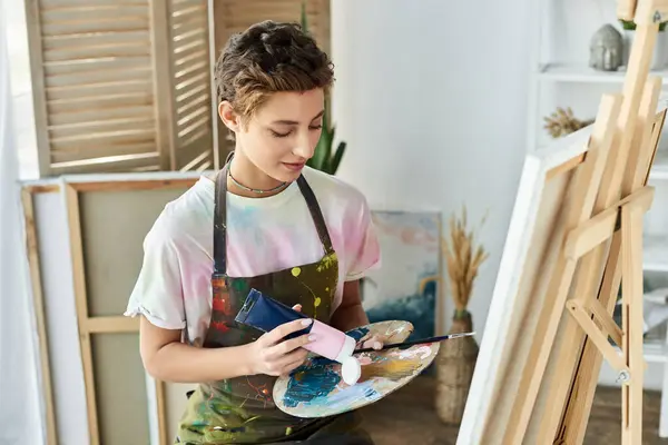 In einem gemütlichen Rahmen konzentriert sich eine junge Frau auf die Malerei und drückt ihre Kreativität mit lebendigen Farben und Werkzeugen aus. — Stockfoto