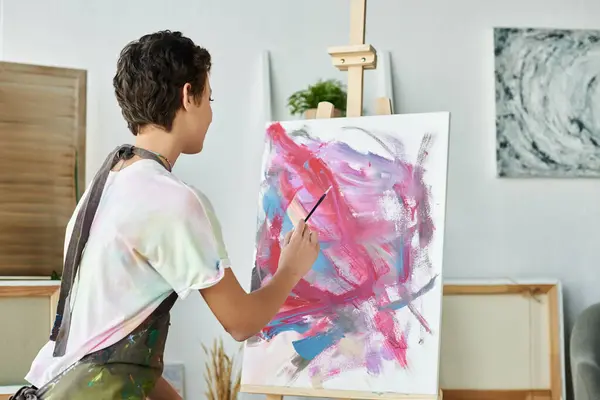 A young woman expresses her creativity by painting a vibrant picture at home during her artistic hobby. — Stock Photo