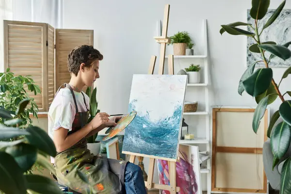 Una joven crea una obra de arte inspirada en el océano en casa, disfrutando de su hobby artístico mientras está rodeada de plantas.. - foto de stock