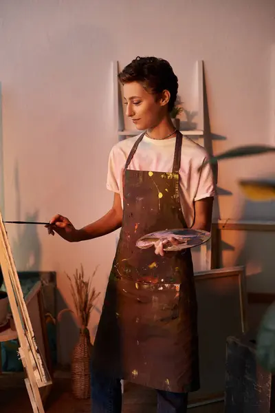 In a cozy home setting, a young woman expresses her creativity by painting with focus and ease. — Stock Photo