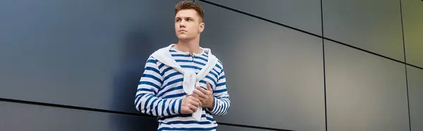 Un joven guapo con una pierna protésica posa pensativamente contra una pared oscura. — Stock Photo