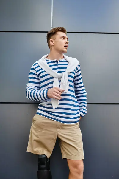 A young, handsome man stands confidently against a modern backdrop, dressed casually. — Stock Photo
