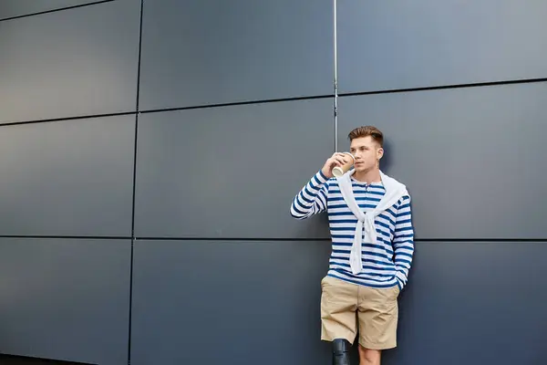 A young man with a prosthetic leg stands relaxed, sipping a drink in a stylish setting. — Stock Photo