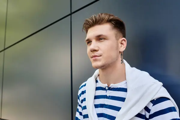 Молодий чоловік з гордістю стоїть на тлі сучасного фону, виключаючи впевненість та індивідуальність. — Stock Photo
