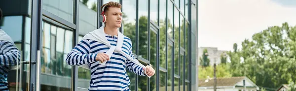 A determined young man jogs along a sleek building, showcasing strength and resilience. — Fotografia de Stock