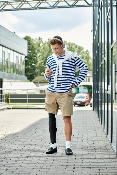 A stylish young man stands outside, confidently using his phone. — Stock Photo