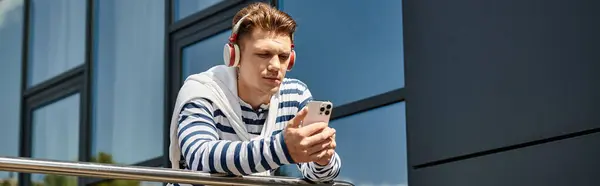 A stylish young man listens to music on headphones, confidently embracing his surroundings. — Stock Photo