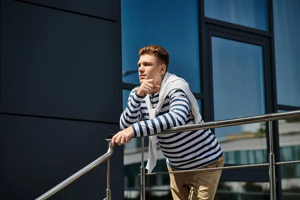 A young man with a prosthetic leg leans pensively on a balcony railing, embracing the sun. — Stock Photo