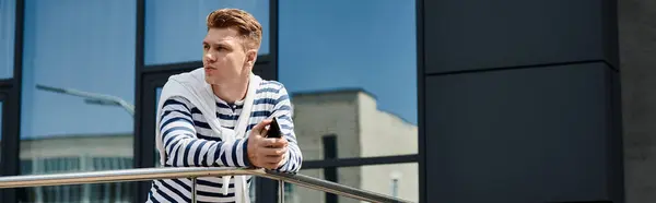 A young, handsome man with a prosthetic leg gazes thoughtfully while holding his phone. — Stock Photo