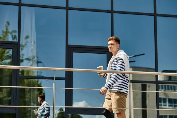 Un joven con una pierna protésica pasea con confianza mientras bebe café en un día brillante. - foto de stock