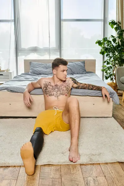 A young man sits on the floor, showcasing his unique style and strength with a prosthetic leg. — Stock Photo