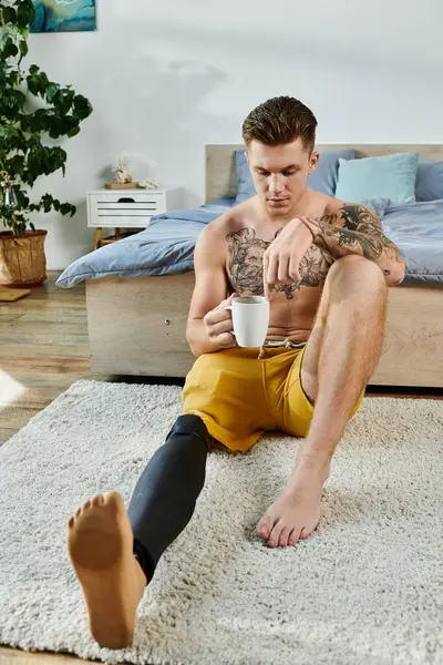 Sitting in a cozy room, a young man with a prosthetic leg contemplates life while sipping tea. — Stock Photo