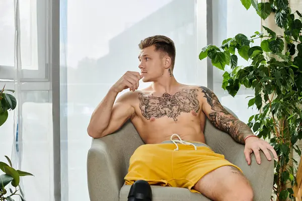 A handsome young man with a prosthetic leg sits thoughtfully in a bright, cozy space. — Stock Photo