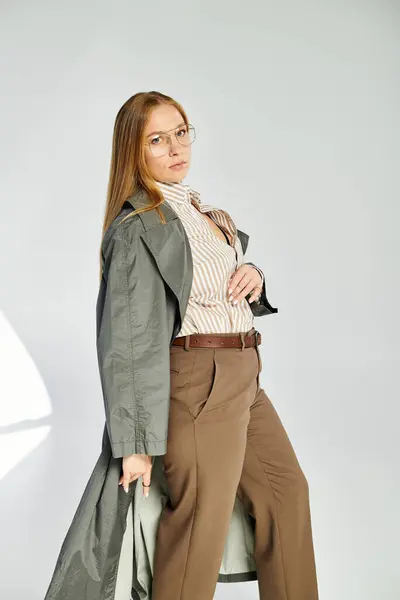 Una donna elegante in abbigliamento autunnale posa con fiducia in uno studio, irradiando eleganza e fascino. — Foto stock