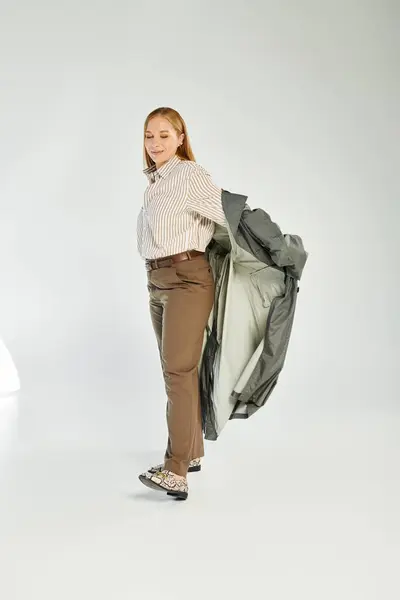 Eine schöne Frau präsentiert ihren schicken Herbst-Look, während sie in einem modernen Studio-Setting verspielt posiert. — Stockfoto