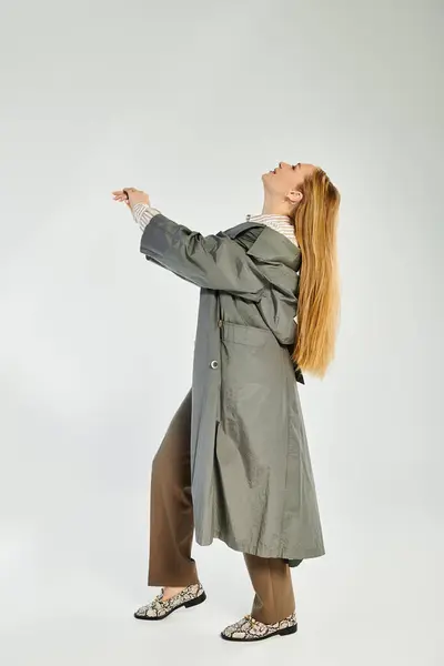 A stylish woman with long hair showcases autumn fashion in a studio, exuding confidence and elegance. — Stock Photo