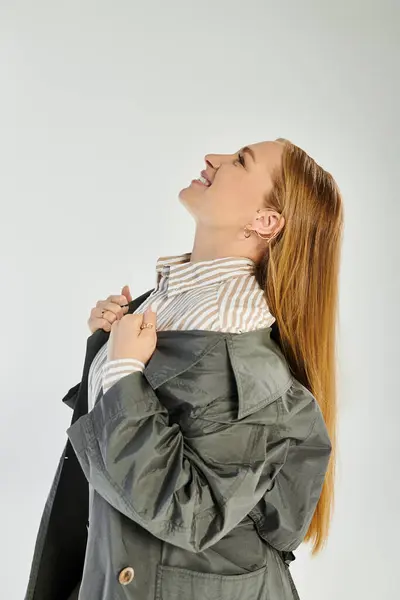 La femme rayonne de confiance dans la mode d'automne élégant, posant gracieusement sur un fond gris doux. — Photo de stock