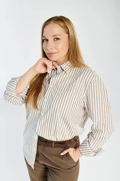 Eine charmante Frau mit langen Haaren präsentiert ihren Stil anmutig in einem Studio-Setting mit grauem Hintergrund. — Stockfoto