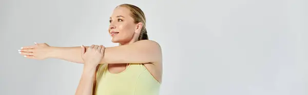 A focused woman in a crop top engages in stretching exercises to enhance her fitness routine. — Stock Photo