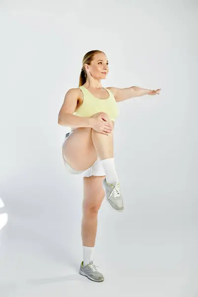 A fit woman enthusiastically performs an exercise in a bright studio, showcasing strength and agility. — Stock Photo
