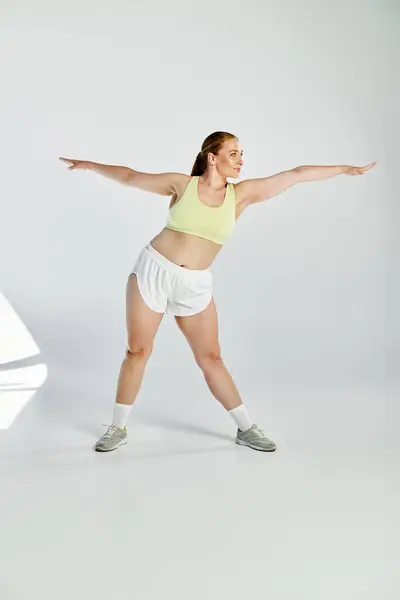 A dedicated sportswoman performs an energetic stretch in a light-filled studio, showcasing her fitness routine. — Stock Photo