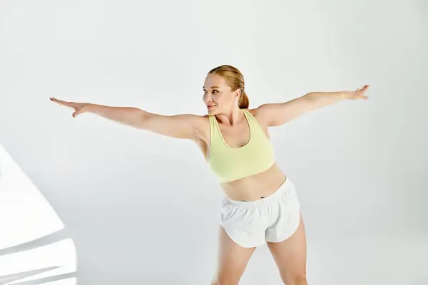 A determined woman in a crop top and shorts performs an energetic exercise in a vibrant studio space. — Stock Photo