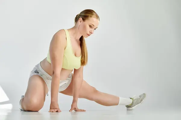 In a bright studio, a focused woman performs a deep stretch, showcasing her dedication to fitness. — Stock Photo