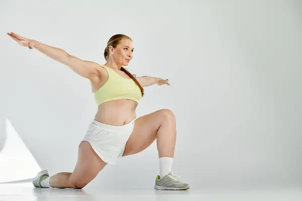 Une femme déterminée exécute un étirement dans un studio spacieux, en se concentrant sur sa routine de fitness. — Photo de stock