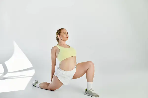 A dedicated woman in a crop top stretches gracefully in a bright studio, showcasing her fitness routine. — Stock Photo