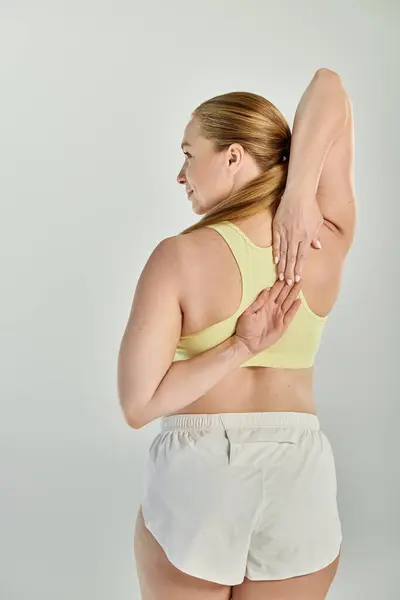 Une sportive dévouée dans un crop top s'engage dans un étirement dynamique, améliorant sa routine de fitness. — Photo de stock