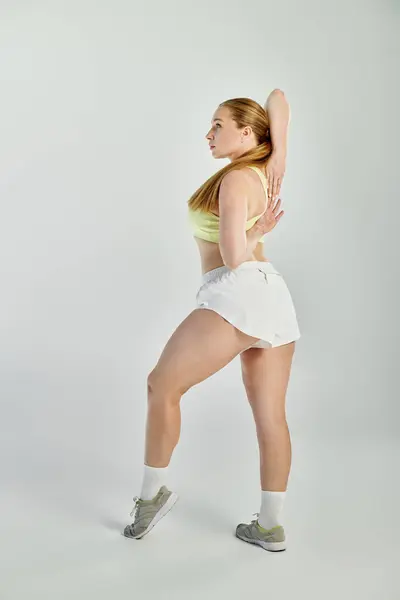 Une femme déterminée effectue un exercice d'étirement dans un studio aéré, mettant en valeur son athlétisme et sa concentration. — Photo de stock