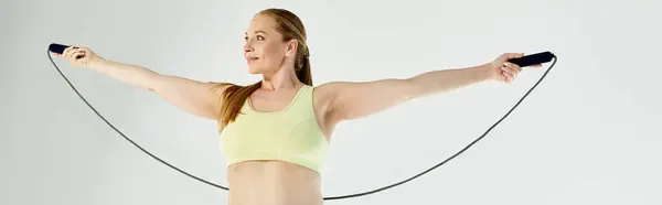 In a bright studio, an active woman practices skipping, demonstrating her dedication to fitness and health. — Stock Photo