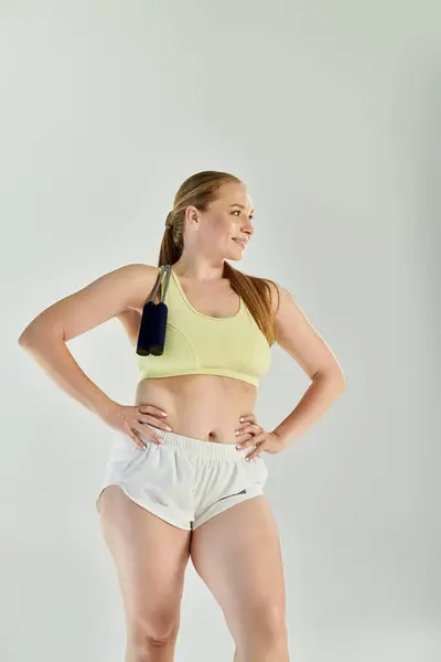 A confident woman in a crop top is actively exercising, displaying strength and focus in a vibrant studio. — Stock Photo