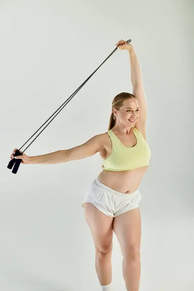 A joyful woman in a crop top practices fitness routines, demonstrating her strength and energy in a vibrant studio. — Stock Photo