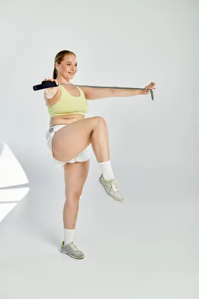 A determined woman in a crop top performs an exercise routine in a bright studio setting, showcasing her energy. — Stock Photo