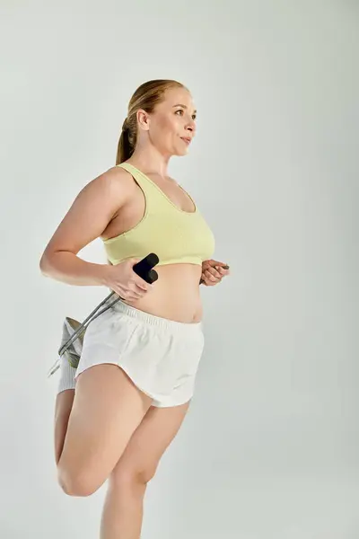 A woman in a crop top exercises energetically in a bright studio, embracing her active lifestyle. — Stock Photo