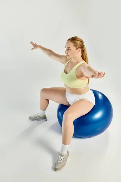 A dedicated sportswoman performs an exciting workout on a vibrant exercise ball, showcasing her strength and focus. — Stock Photo
