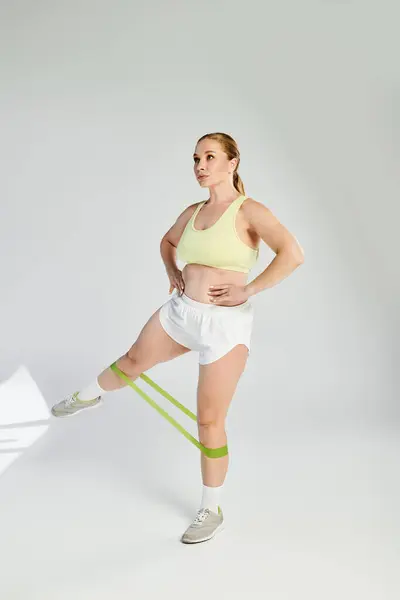 A determined sportswoman in a crop top is working out using resistance bands in a bright studio. — Stock Photo