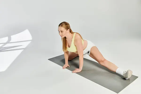 Donna energica pratica la flessibilità con un tratto profondo in uno studio vibrante, mostrando la sua dedizione. — Foto stock