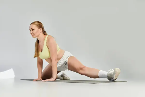 A dedicated sportswoman stretches her body in a bright studio, emphasizing fitness and determination. — Stock Photo