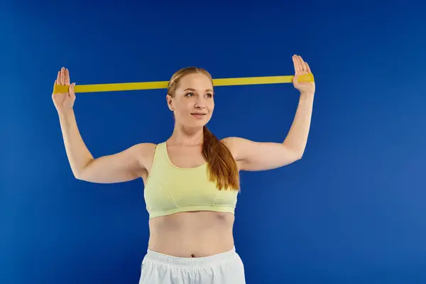 A determined woman in a crop top engages in resistance band training, showcasing strength and focus. — Stock Photo